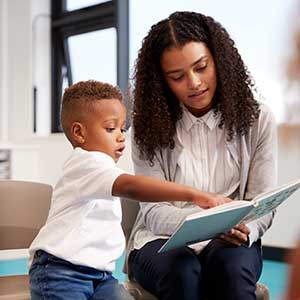 Teacher with nursery student reading a book