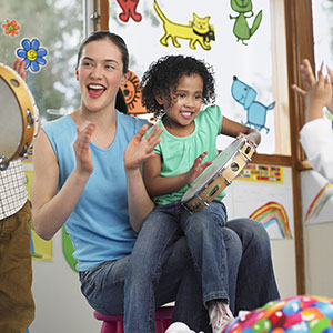 Teacher and little girl playing tamborine at Smart Kids Day Nursery